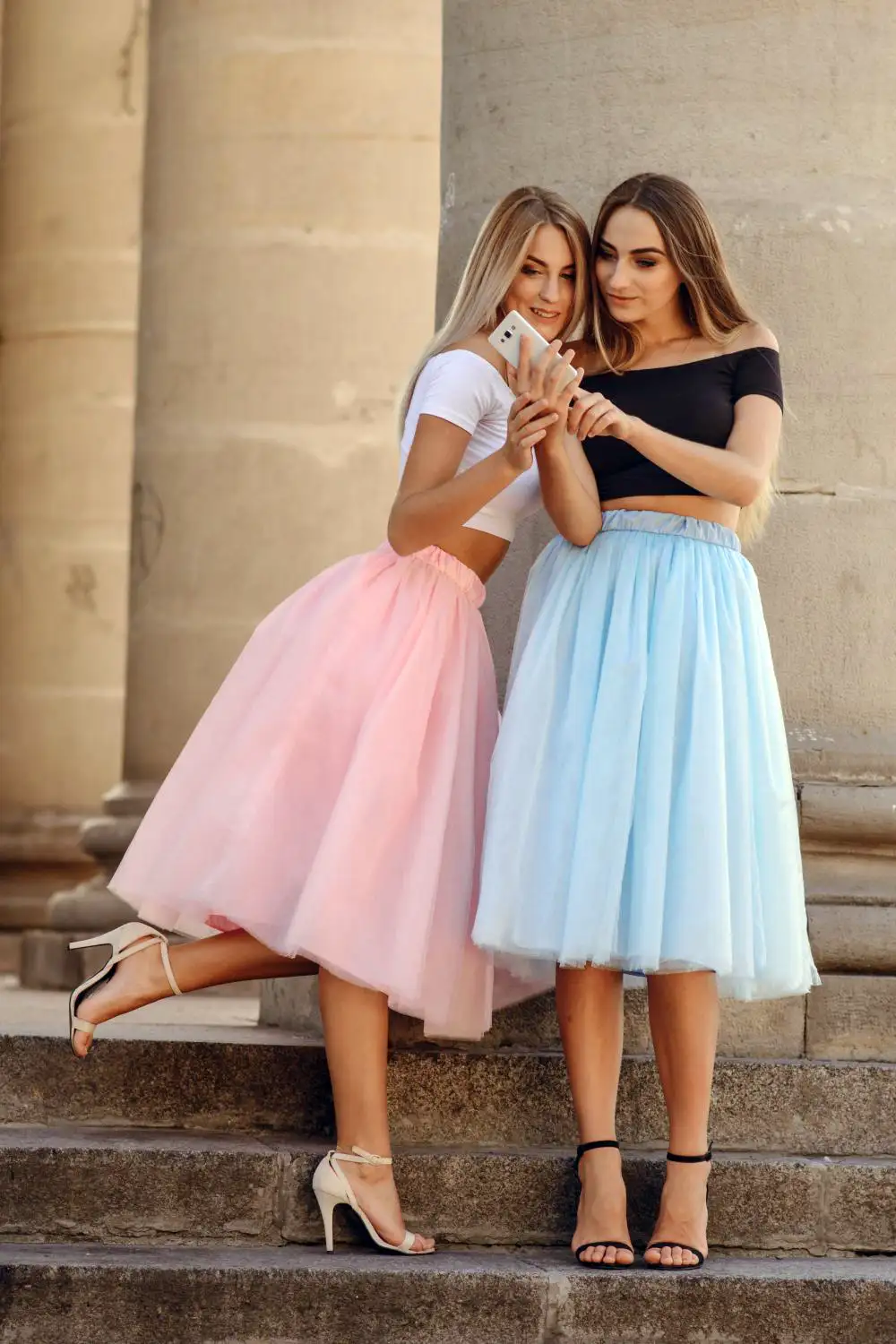 Two girls watching phone wearing flared skirts