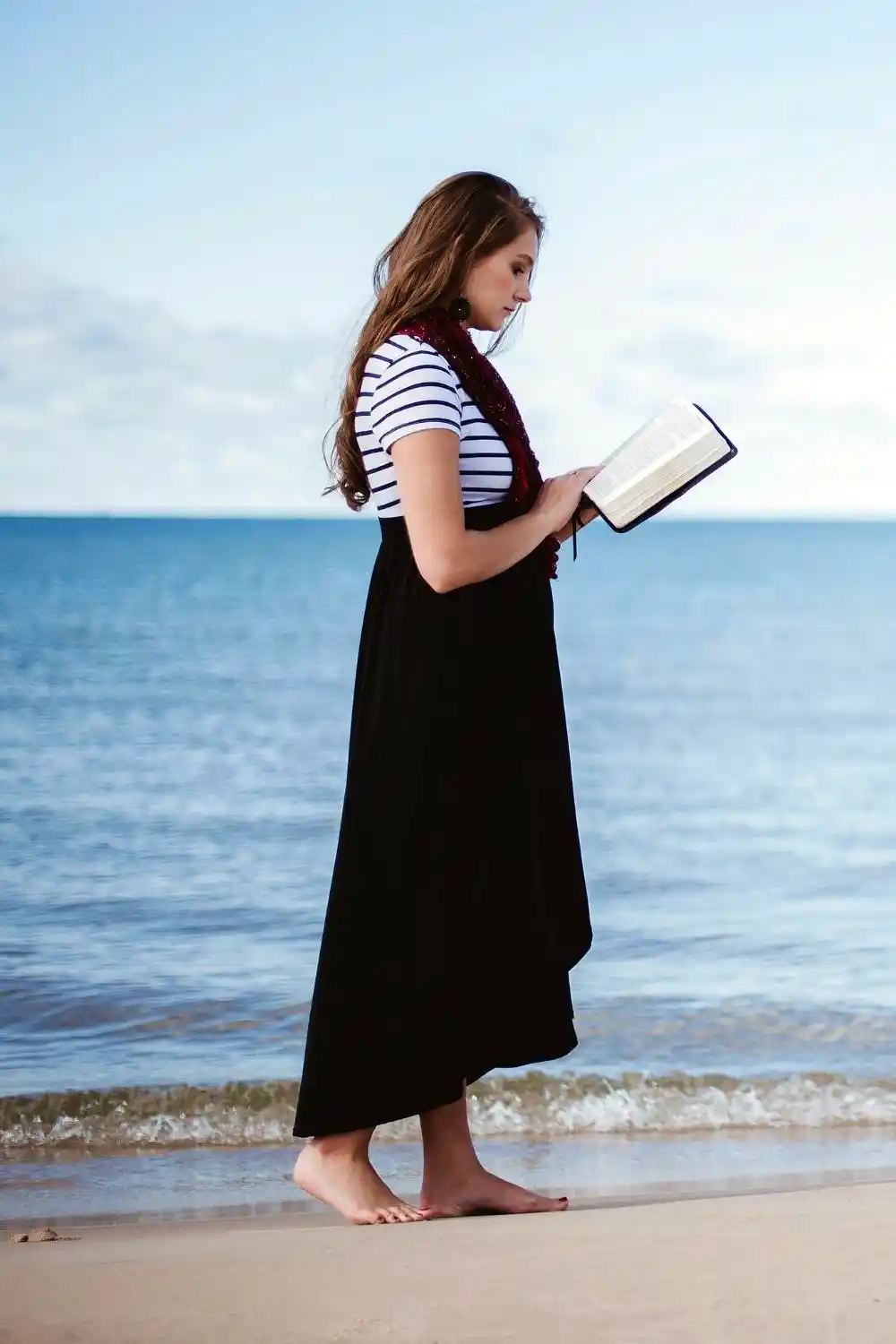 Women wearing long dress and reading Bible at the beach