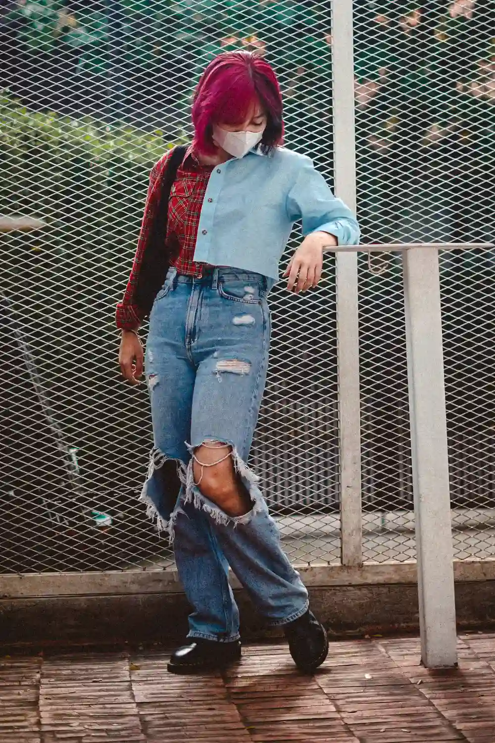 Woman in Ripped Denim Jeans Leaning on a Metal Post
