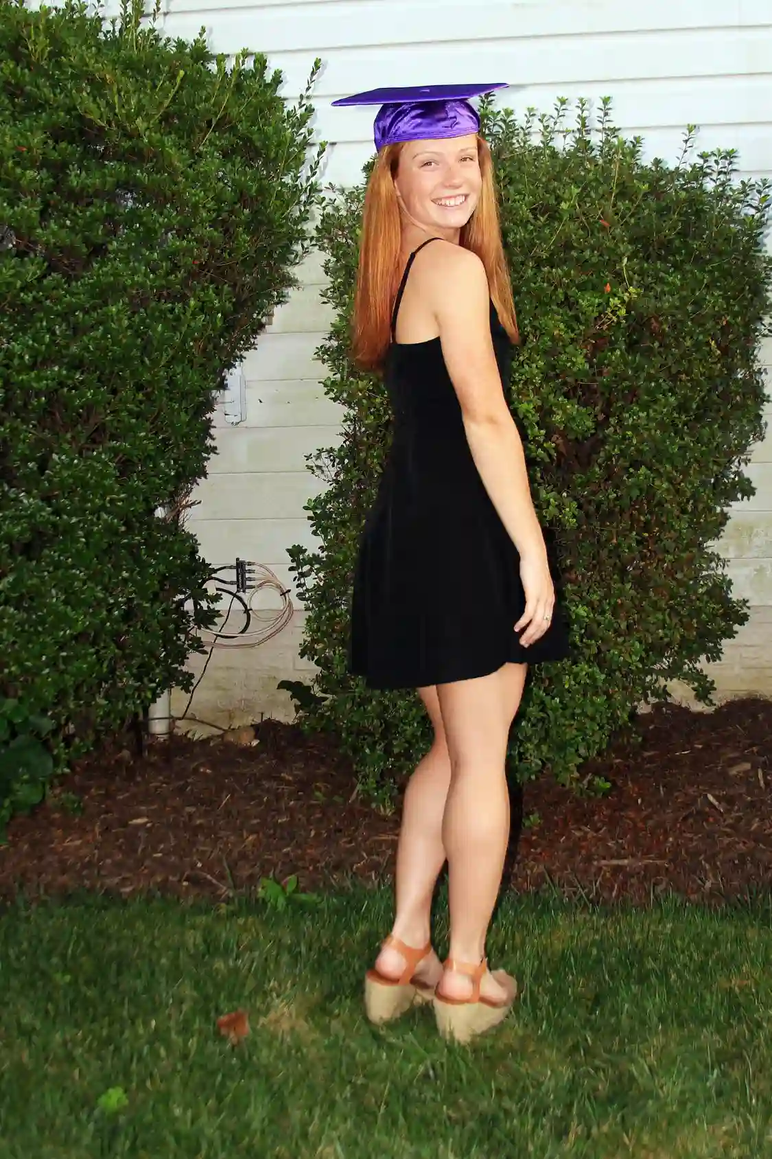 Young lady wearing a little black dress and graduation cap
